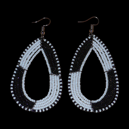 Longues boucles d'oreilles kenyanes en perles de rocaille blanches et noires enfilées sur plusieurs rangées de fils de fer montés en forme de gouttes. Ces boucles d'oreilles bicolores mesurent 8 cm de long et 4 cm de large et se portent avec des crochets en acier inoxydable sur des oreilles percées.
