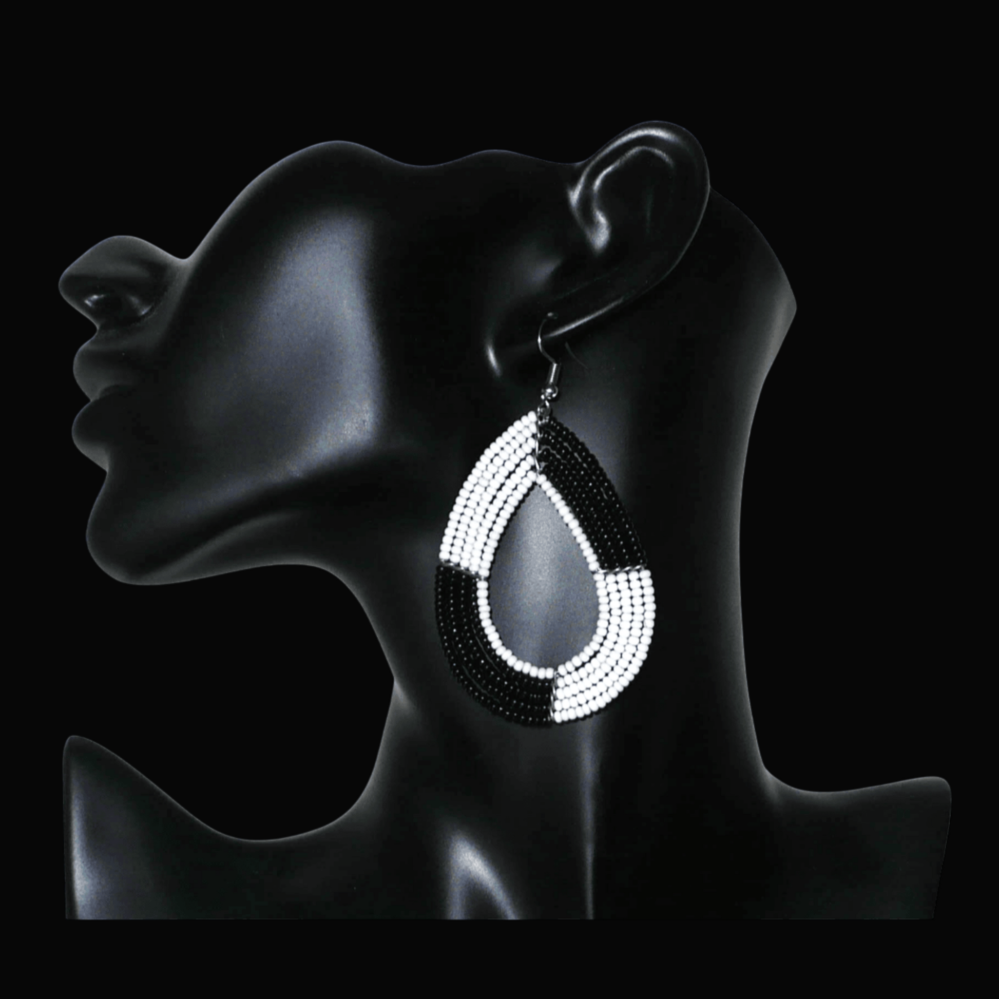 Longues boucles d'oreilles bicolores noires et blanches en forme de gouttes faites de perles de rocaille ; elles mesurent 8 cm de long et 4 cm de large, et se portent sur des oreilles percées.
