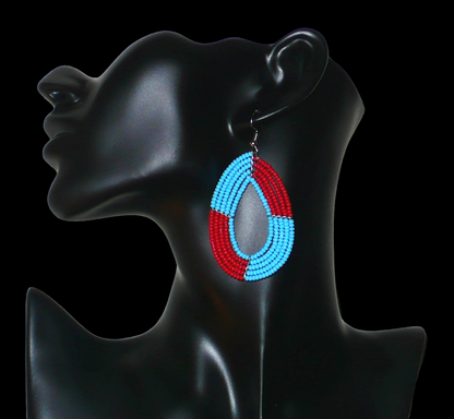 Boucles d'oreilles bicolores évoquant les années 60, composées de perles de rocaille rouges et bleues glissées sur cinq rangées de fils de fer montés en forme de gouttes. Elles mesurent 7,5 cm de long et 4 cm de large et se portent avec des crochets en acier inoxydable. 