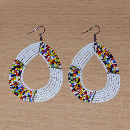 Longues et larges boucles d'oreilles multi-rangs blanches et multicolores faites de perles de rocaille montées en forme de gouttes. Ces boucles d'oreilles mesurent 8,5 cm de long et 5 cm de large et se portent avec de crochets en acier inoxydable sur des oreilles percées.