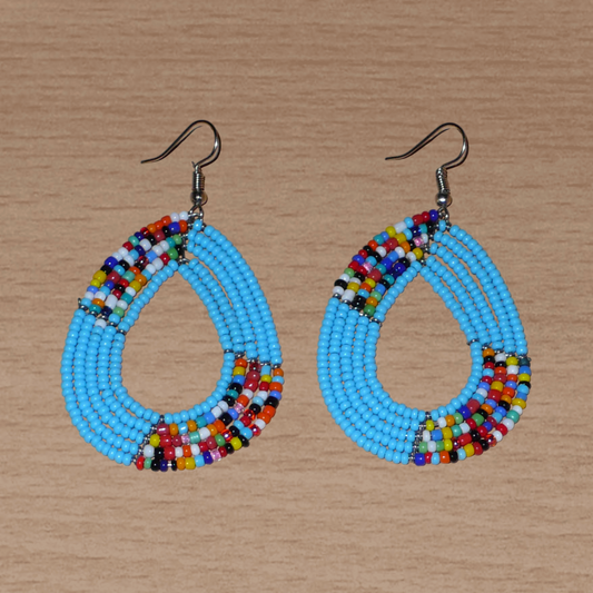 Boucles d'oreilles bleu ciel et multicolores composées de perles de rocaille enfilées sur cinq rangées de fils de fer montés en forme de gouttes. Elles mesurent 7 cm de long et 4 cm de large et se portent sur des oreilles percées.