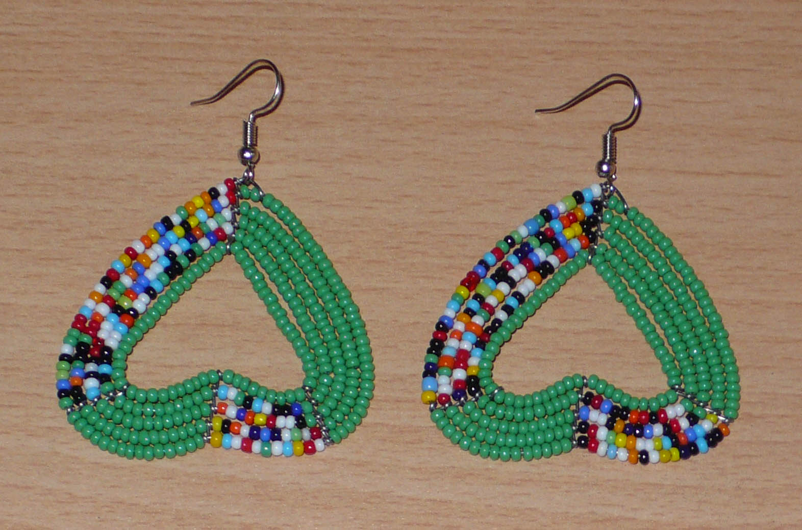 Boucles d'oreilles perlées en forme de coeurs inversés composées de perles de rocaille vertes et multicolores. De taille moyennes, elles mesurent 6,5 cm de long et 5 cm de large.