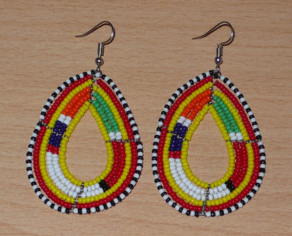 Boucles d'oreilles africaines traditionnelles jaunes et multicolores à motifs ethniques Massai, composées de perles de rocaille montées en forme de gouttes. Elles mesurent 7.5 cm de long et 4.5 cm de large, et se portent sur des oreilles percées.