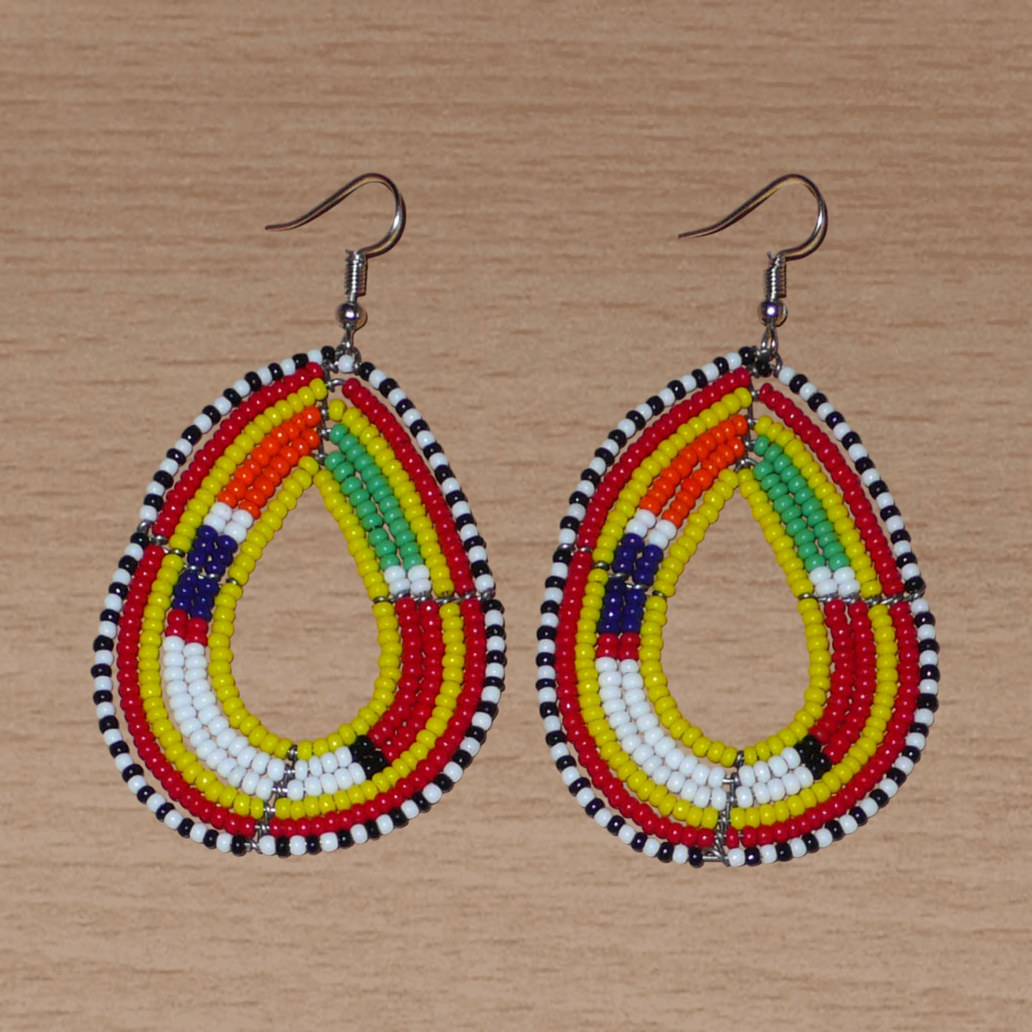 Boucles d'oreilles africaines traditionnelles jaunes et multicolores à motifs ethniques Massai, composées de perles de rocaille montées en forme de gouttes. Elles mesurent 7.5 cm de long et 4.5 cm de large, et se portent sur des oreilles percées.