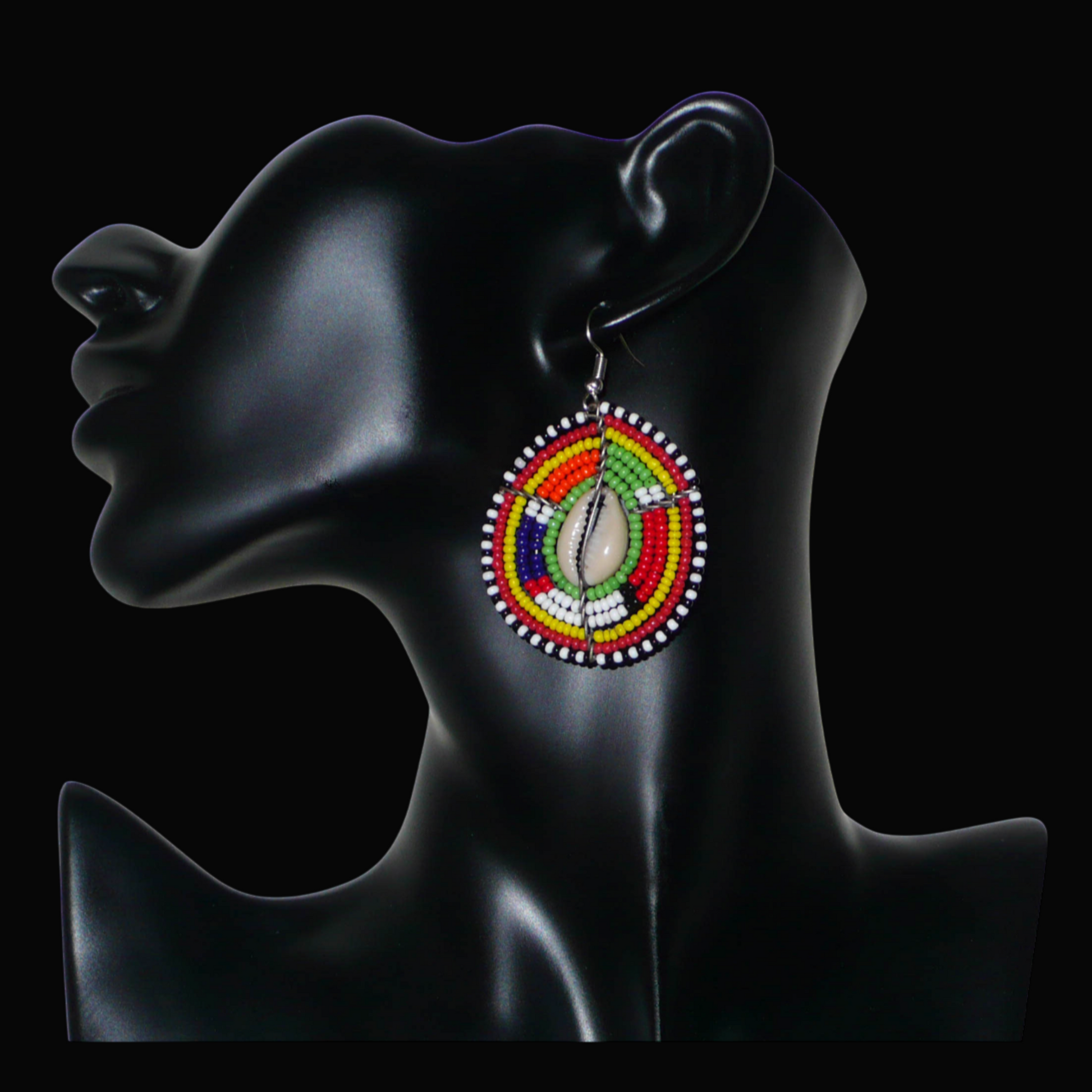 Boucles d'oreilles africaines ethniques aux motifs tribaux traditionnels caractéristiques de l'artisanat Massai. Confectionnées au Kenya, elles sont composées de perles de rocaille vertes et multicolores et de coquillages cauris fixés sur des fils de fer montés en forme de boucliers Massai. De taille moyenne, elles mesurent 6 cm de long et 4 cm de large, et se portent avec des crochets en acier inoxydable sur des oreilles percées.
