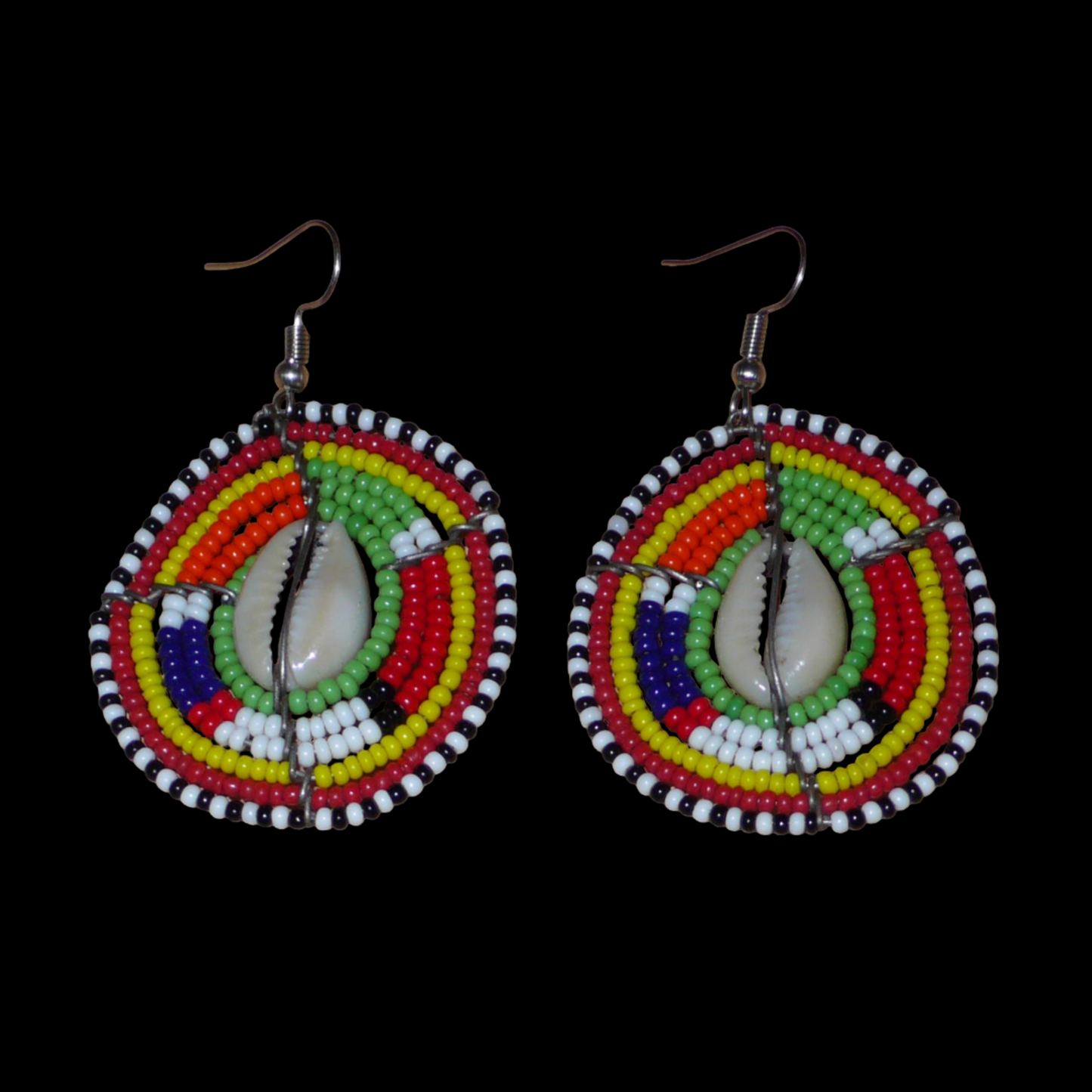 Boucles d'oreilles africaines ethniques aux motifs tribaux traditionnels caractéristiques de l'artisanat Massai. Confectionnées au Kenya, elles sont composées de perles de rocaille vertes et multicolores et de coquillages cauris fixés sur des fils de fer montés en forme de boucliers Massai. De taille moyenne, elles mesurent 6 cm de long et 4 cm de large, et se portent avec des crochets en acier inoxydable sur des oreilles percées.