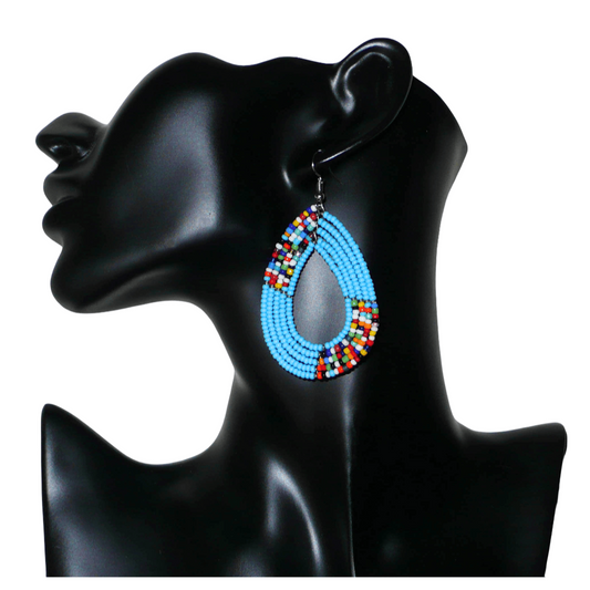 Boucles d'oreilles kenyanes multi-rangs en perles de rocaille bleu ciel et multicolores. Elles mesurent 7 cm de long et 4 cm de large et se portent sur des oreilles percées.