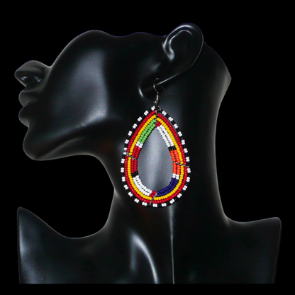 Boucles d'oreilles africaines à motifs ethniques Massai composées de perles de rocaille multicolores glissées sur cinq rangées de fils de fer montés en forme de gouttes. Elles mesurent 8.5 cm de long et 4.5 cm de large, et se portent avec des crochets en acier inoxydable sur des oreilles percées.