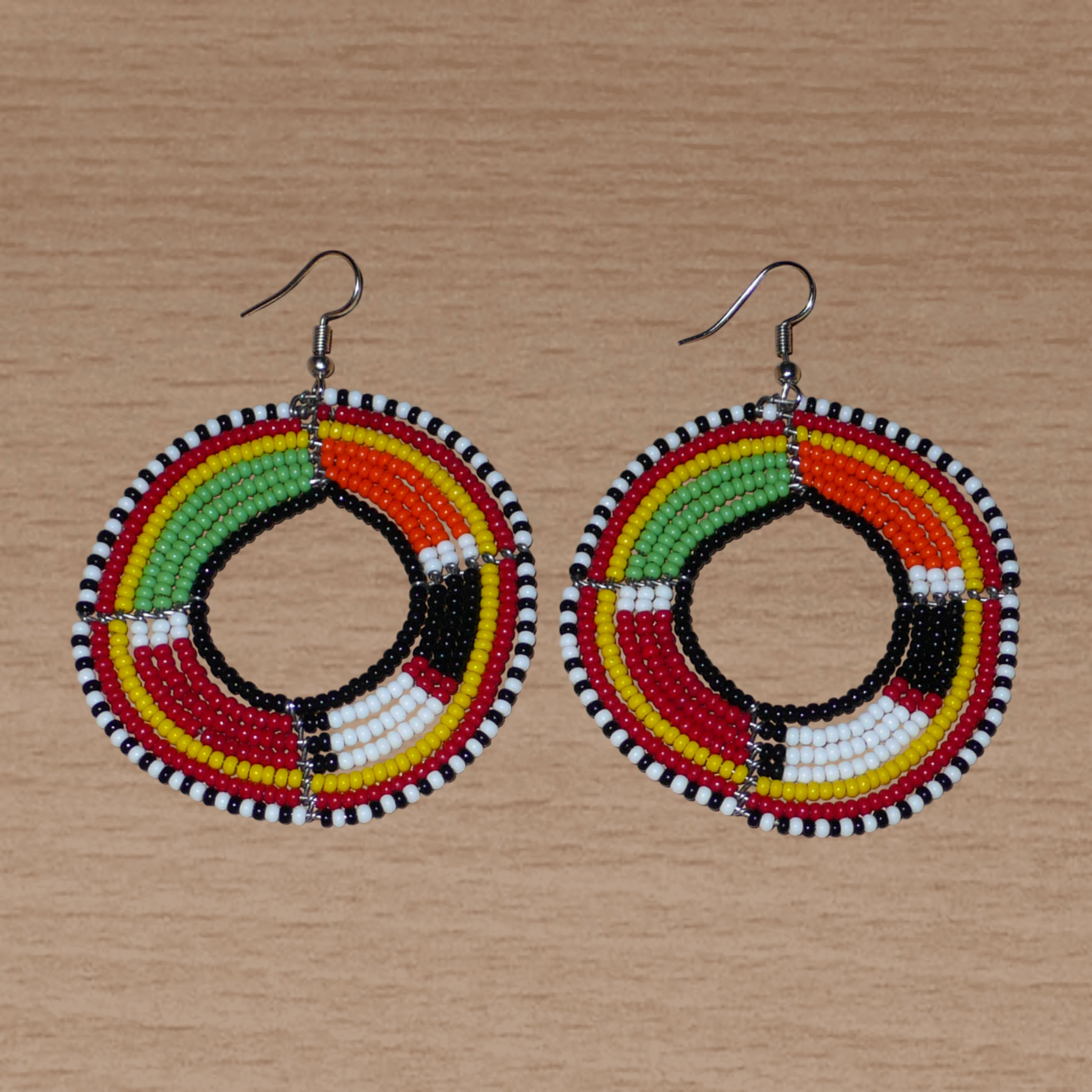 Boucles d'oreilles africaines à motifs ethniques Massai composées de perles de rocaille multicolores montées en forme de cercles. Elles mesurent 7,5 cm de long et 5,5 cm de large et se portent avec des crochets en acier inoxydable sur des oreilles percées.