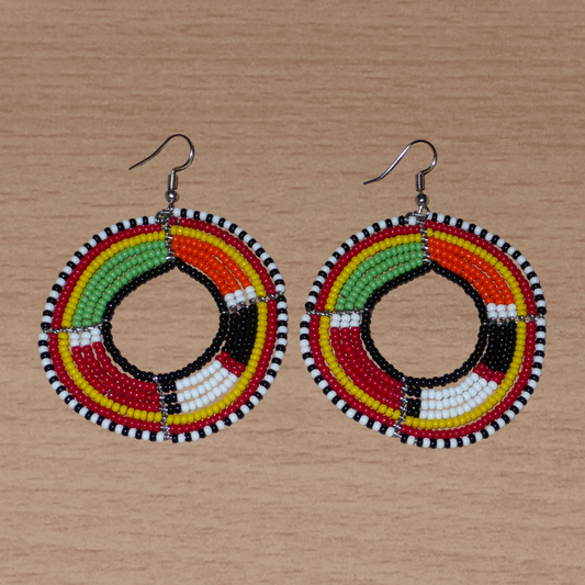 Boucles d'oreilles africaines à motifs ethniques Massai composées de perles de rocaille multicolores montées en forme de cercles. Elles mesurent 7,5 cm de long et 5,5 cm de large et se portent avec des crochets en acier inoxydable sur des oreilles percées.