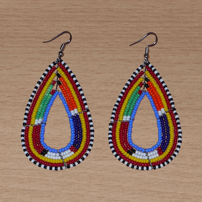 Boucles d'oreilles africaines Massai en forme de gouttes composées de perles de rocaille bleues et multicolores. Elles mesurent 8.5 cm de long et 4 cm de large, et se portent sur des oreilles percées.