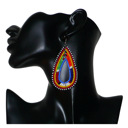 Boucles d'oreilles africaines Massai en forme de gouttes composées de perles de rocaille bleues et multicolores. Elles mesurent 8.5 cm de long et 4 cm de large, et se portent sur des oreilles percées.