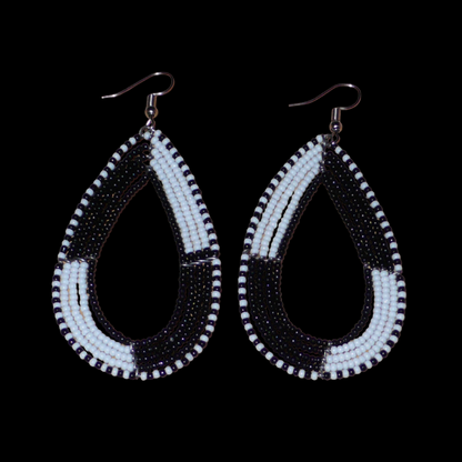 Longues boucles d'oreilles bicolores en forme de gouttes composées de perles de rocaille noires et blanches. Ces boucles d'oreilles mesurent 8 cm de long et 4 cm de large ; elles se portent sur des oreilles percées.