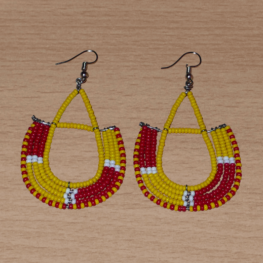 Boucles d'oreilles ethniques tricolores en forme d'ancres composées de perles de rocaille jaunes, rouges et blanches ; elles mesurent 7,5 cm de long et 4 cm de large et se portent avec des crochets en acier inoxydable sur.des oreilles percées.