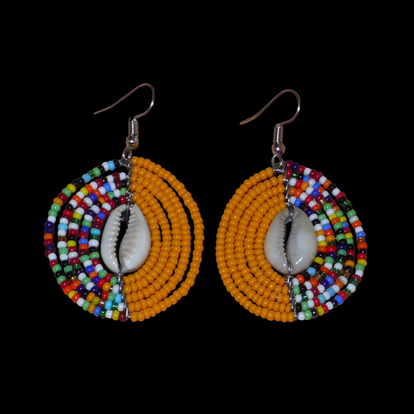 Boucles d'oreilles ethniques orange et multicolores fabriquées au Kenya composées de perles de rocaille et de coquillages cauris. De taille moyenne, elles mesurent 6 cm de long et 3,5 cm de large et se portent sur des oreilles percées.