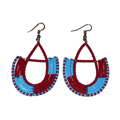 Boucles d'oreilles africaines Massai rouges et bleues composées de perles de rocaille glissées sur des structures géométriques en fils de fer montées en forme d'ancres. Ces boucles d'oreilles bicolores mesurent 7,5 cm de long et 4 cm de large et se portent avec des crochets en acier inoxydable.