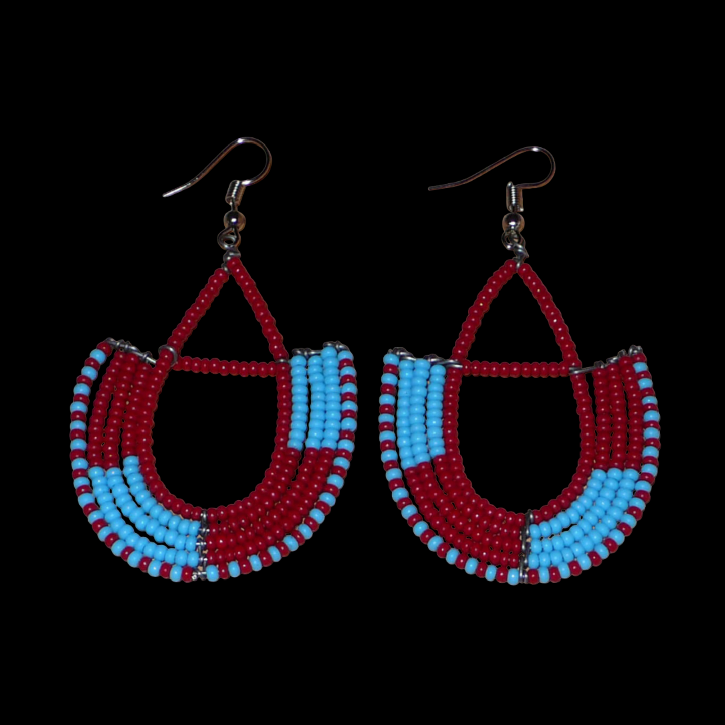 Boucles d'oreilles africaines Massai rouges et bleues composées de perles de rocaille glissées sur des structures géométriques en fils de fer montées en forme d'ancres. Ces boucles d'oreilles bicolores mesurent 7,5 cm de long et 4 cm de large et se portent avec des crochets en acier inoxydable.