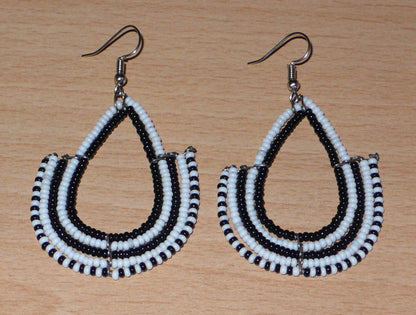 Boucles d'oreilles ethniques bicolores de conception artisanale kenyane : elles se composent de perles de rocaille noires et blanches montées en forme d'ancres. De taille moyenne, cette paire de boucles d'oreilles aux accents ethniques chic mesure 7 cm de long et 4 cm de large, et se porte avec des crochets en acier inoxydable sur des oreilles percées.