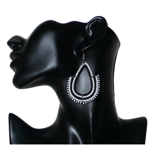 Boucles d'oreilles ethniques bicolores de conception artisanale kenyane : elles se composent de perles de rocaille noires et blanches montées en forme d'ancres. De taille moyenne, cette paire de boucles d'oreilles aux accents ethniques chic mesure 7 cm de long et 4 cm de large, et se porte avec des crochets en acier inoxydable sur des oreilles percées.