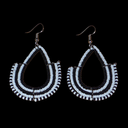 Boucles d'oreilles ethniques bicolores de conception artisanale kenyane : elles se composent de perles de rocaille noires et blanches montées en forme d'ancres. De taille moyenne, cette paire de boucles d'oreilles aux accents ethniques chic mesure 7 cm de long et 4 cm de large, et se porte avec des crochets en acier inoxydable sur des oreilles percées.
