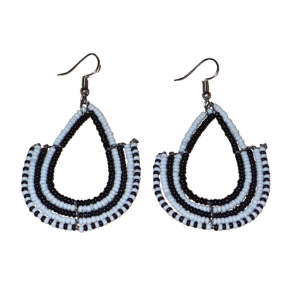 Boucles d'oreilles ethniques bicolores de conception artisanale kenyane : elles se composent de perles de rocaille noires et blanches montées en forme d'ancres. De taille moyenne, cette paire de boucles d'oreilles aux accents ethniques chic mesure 7 cm de long et 4 cm de large, et se porte avec des crochets en acier inoxydable sur des oreilles percées.