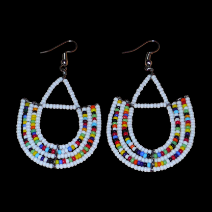 Boucles d'oreilles ethniques blanches et multicolores composées de perles de rocaille montées en forme d'ancres. Ces boucles d'oreilles mesurent 7 cm de long et 4 cm de large ; elles se portent avec des crochets en acier inoxydable sur des oreilles percées.
