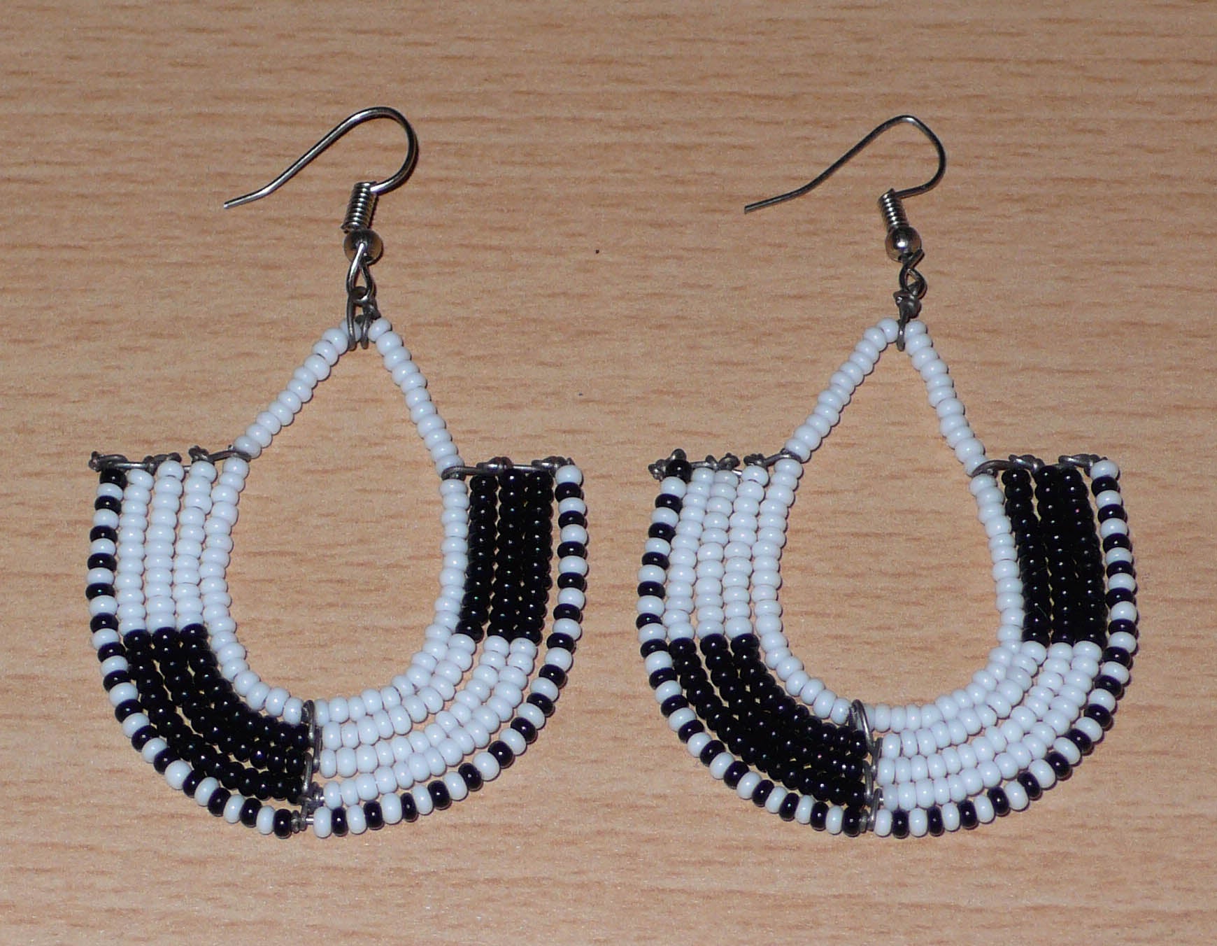 Boucles d'oreilles kenyanes au style ethnique chic composées de perles de rocaille blanches et multicolores. Elles mesurent 7 cm de long et 4 cm de large et se portent sur des oreilles percées.