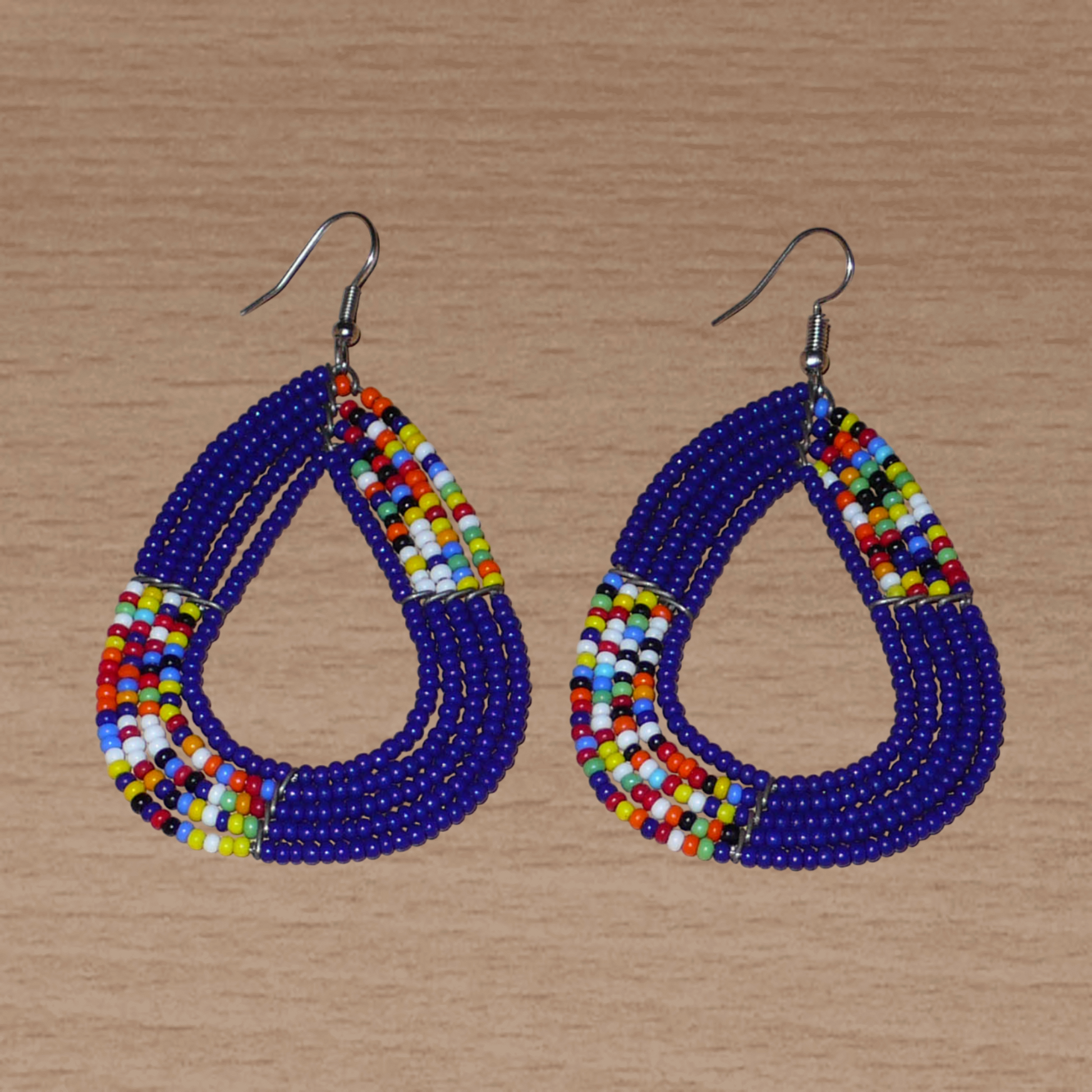 Boucles d'oreilles kenyanes composées de perles de rocaille bleu foncé et multicolores glissées sur cinq rangées de fils de fer montés en forme de triangles aux angles arrondis. Elles mesurent 8 cm de long et 4,5 cm de large, et se portent avec des crochets en acier inoxydable sur des oreilles percées.