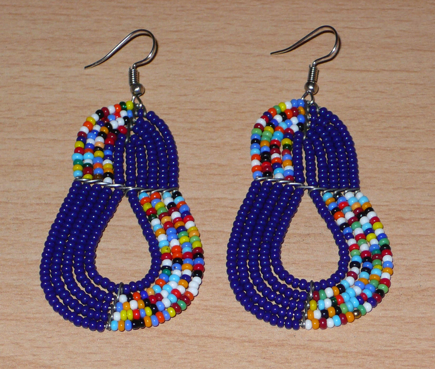 Boucles d'oreilles ethniques bleu marine et multicolores : de fabrication artisanale kenyane Massai, elles se composent de perles de rocaille glissées sur plusieurs rangées de fils de fer. Ces boucles d'oreilles aux accents afro bohème mesurent 8 cm de long et 3.5 cm de large, et se portent avec des crochets en acier inoxydable sur des oreilles percées.