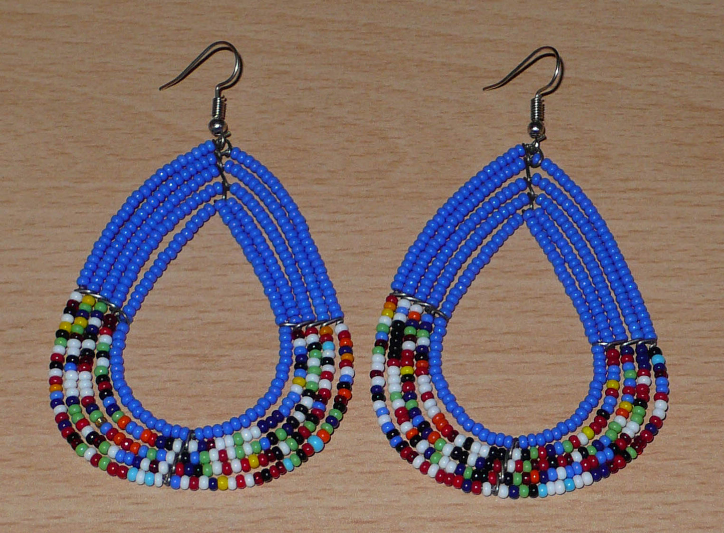 Boucles d'oreilles ethniques multi-rangs bleues et multicolores en perles de rocaille. Elles mesurent 8.5 cm de long et 5 cm de large, et se portent sur des oreilles percées.