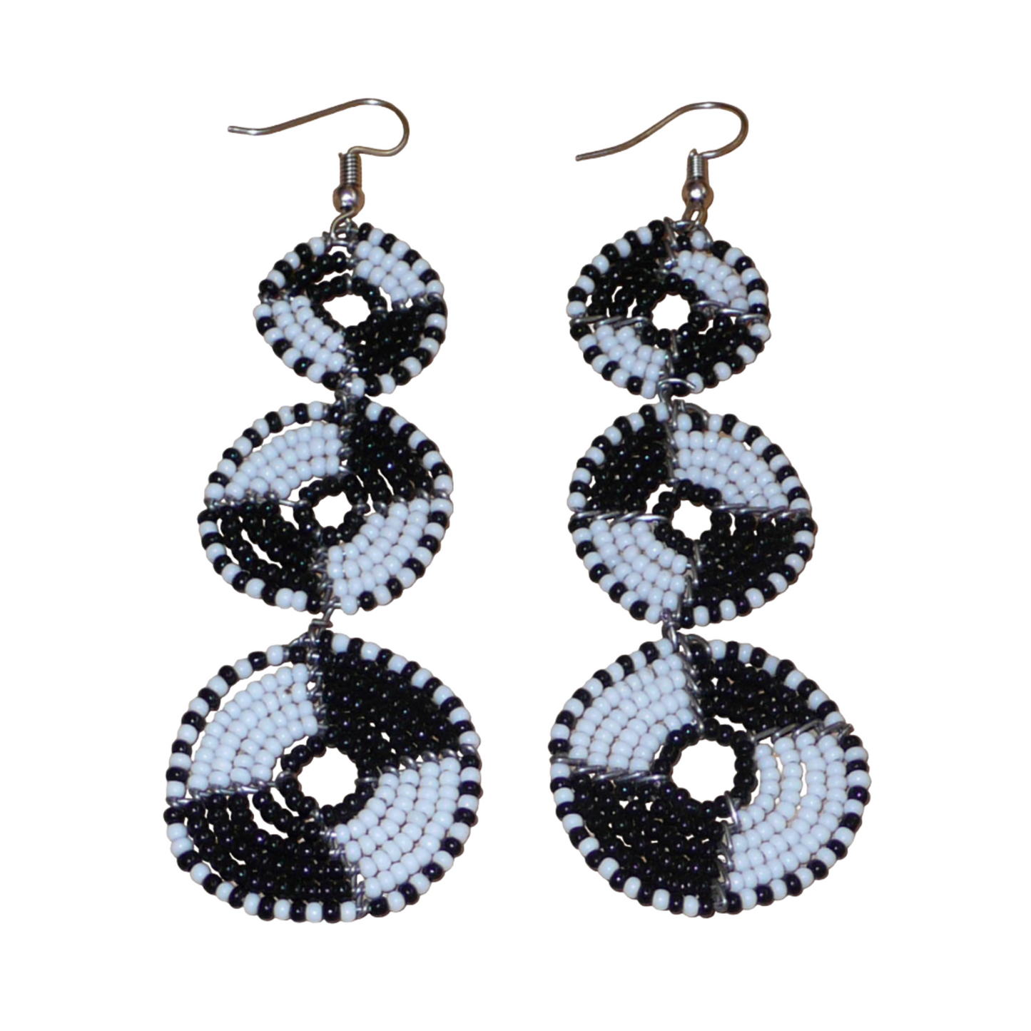 Longues boucles d'oreilles ethniques Massai composées de perles noires et blanches montées en cercles superposés. Ces boucles d'oreilles bicolores mesurent 9,5 cm de long et 3 cm de large ; elles se portent avec des crochets sur des oreilles percées.