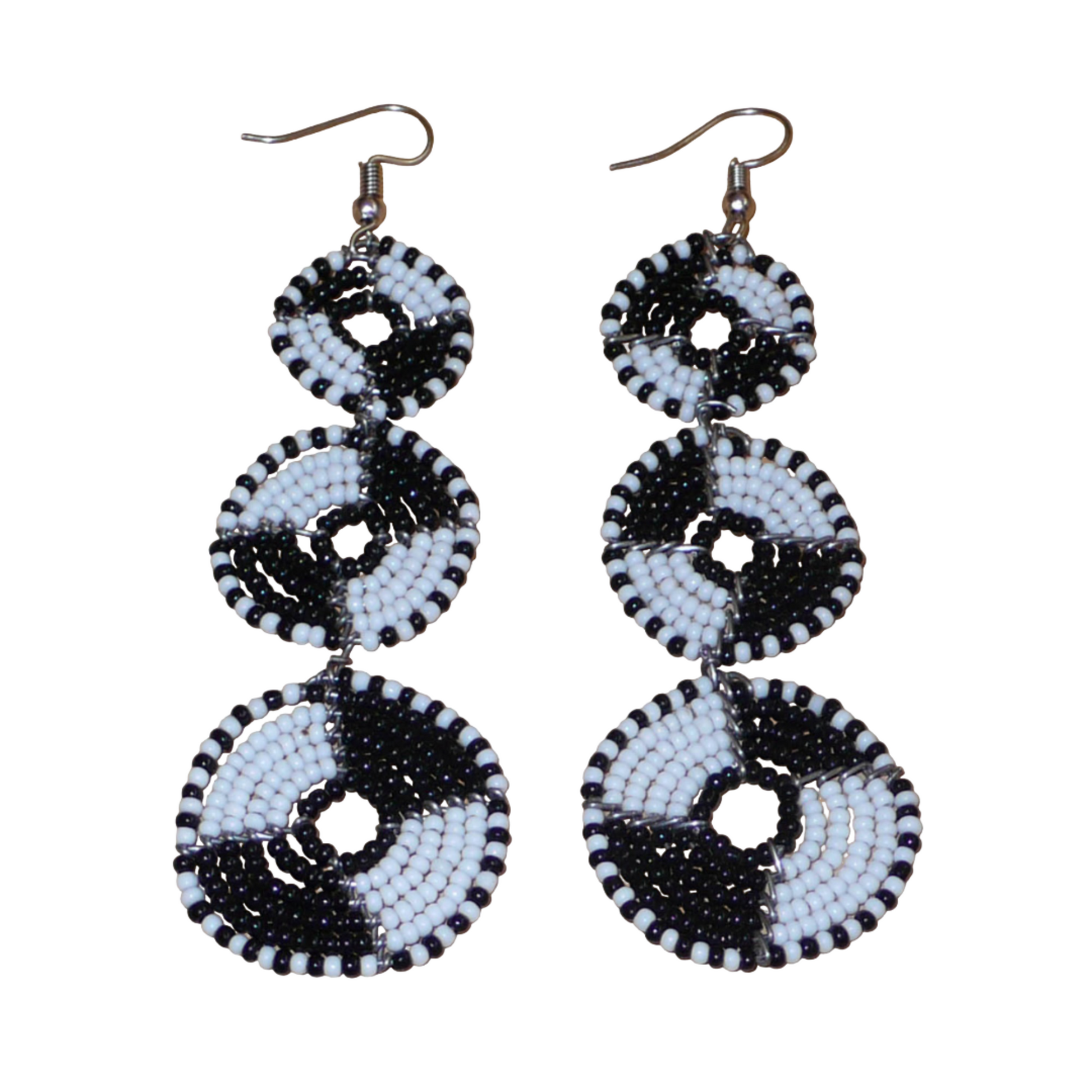 Longues boucles d'oreilles ethniques Massai composées de perles noires et blanches montées en cercles superposés. Ces boucles d'oreilles bicolores mesurent 9,5 cm de long et 3 cm de large ; elles se portent avec des crochets sur des oreilles percées.
