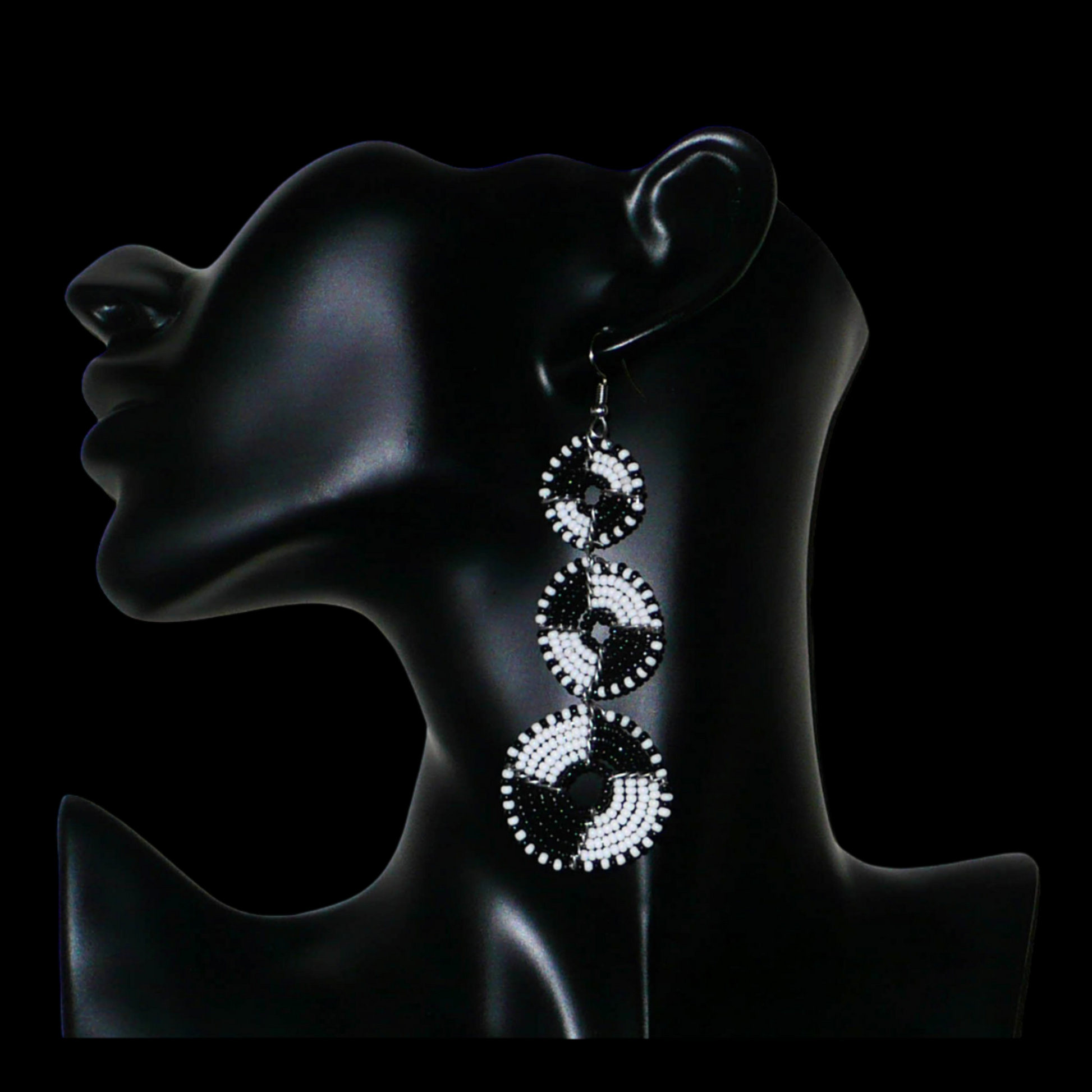 Longues boucles d'oreilles ethniques Massai composées de perles noires et blanches montées en cercles superposés. Ces boucles d'oreilles bicolores mesurent 9,5 cm de long et 3 cm de large ; elles se portent avec des crochets sur des oreilles percées.