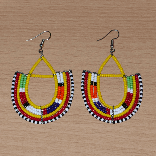 Boucles d'oreilles africaines traditionnelles aux couleurs ethniques et motifs Massai rappelant le style afro chic des années 70 : elles se composent de perles de rocaille jaunes et multicolores fixées sur des structures en fils de fer en forme d'ancres. Elles mesurent 7.5 cm de long et 4.5 cm de large, elles se portent avec des crochets en acier inoxydable sur des oreilles percées.