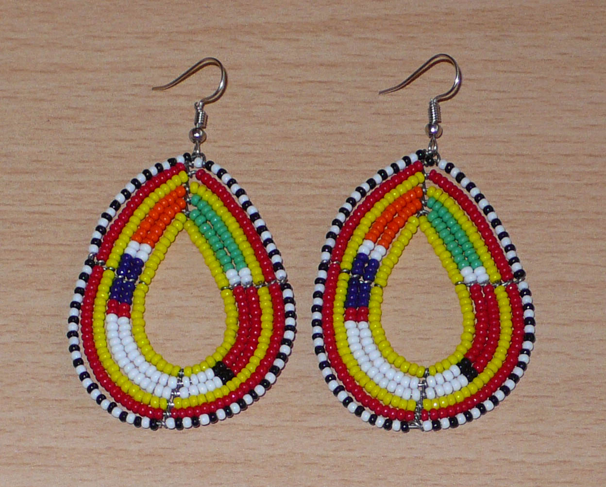 Boucles d'oreilles ethniques de tradition Massai en forme de gouttes faites de perles de rocaille jaunes et multicolores. Elles mesurent 8 cm de long et 4 cm de large et se portent avec des crochets en acier inoxydable sur des oreilles percées. Timeless Fineries