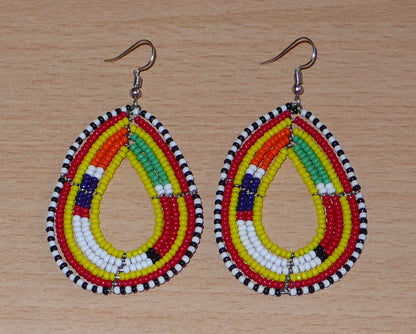 Boucles d'oreilles ethniques de tradition Massai en forme de gouttes faites de perles de rocaille jaunes et multicolores. Elles mesurent 8 cm de long et 4 cm de large et se portent avec des crochets en acier inoxydable sur des oreilles percées. 