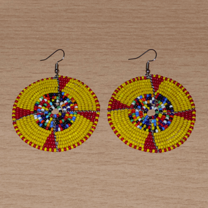 Boucles d'oreilles ethniques kenyanes en perles de rocaille principalement jaunes, puis rouges et multicolores enfilées sur des structures circulaires en fils de fer. Elles mesurent 7.5 cm de long et se portent sur des oreilles percées.