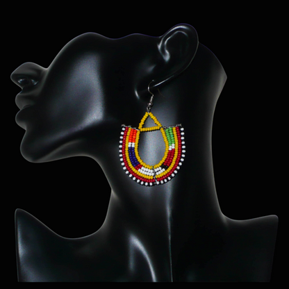 Cette paire de boucles d'oreilles africaines traditionnelles, de fabrication artisanale Massai, apportera une touche ethnique à votre look ! Ces boucles d'oreilles aux accents exotiques se composent de perles de rocaille jaunes et multicolores glissées sur des fils de fer montés en forme d'ancres. Elles mesurent 7 cm de long et 4.5 cm de large, et se portent avec des crochets en acier inoxydable sur des oreilles percées.