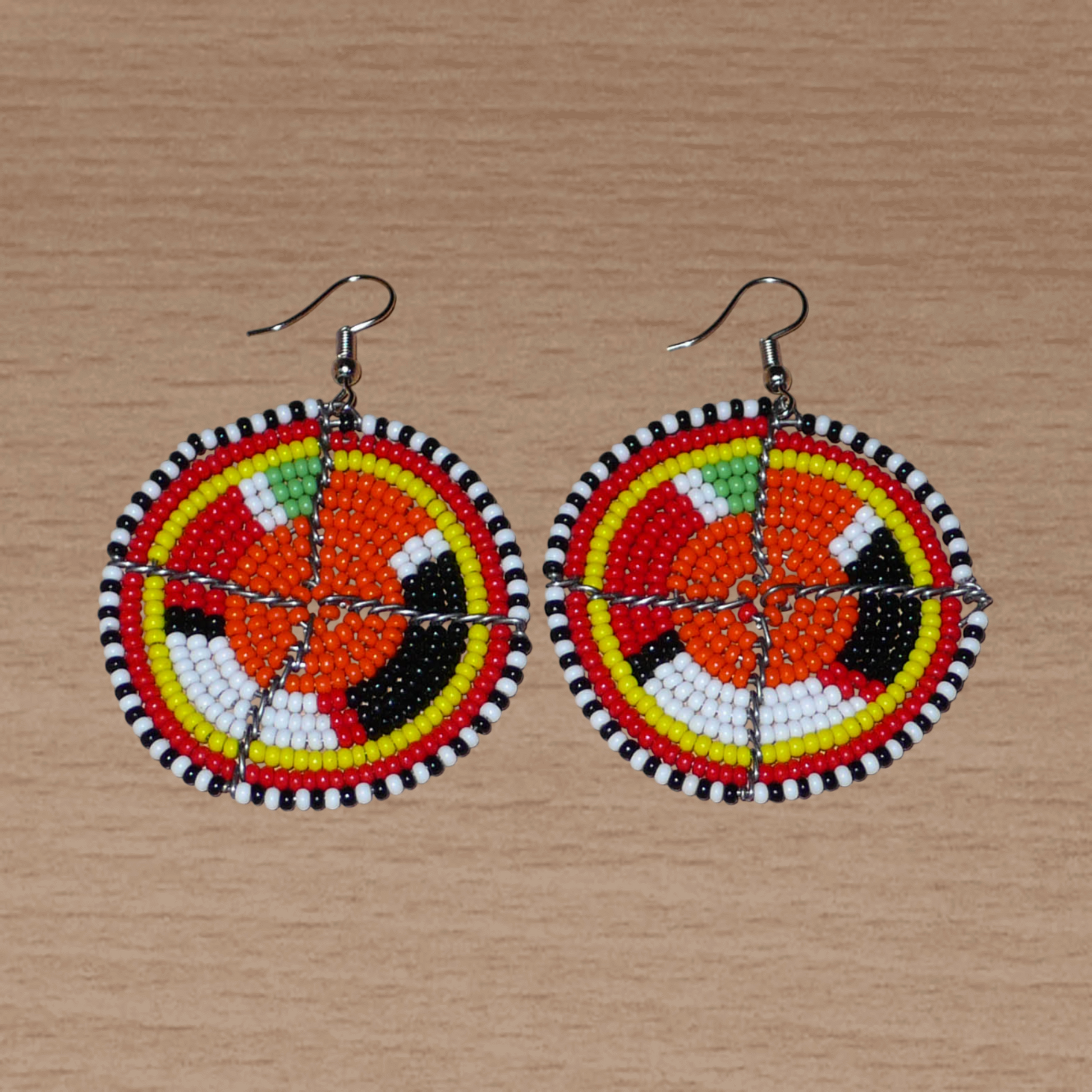 Boucles d'oreilles africaines Massai rondes en perles de rocaille orange et multicolores ; de taille moyenne, elles mesurent 6,5 cm de long et 4,5 cm de large, et se portent avec des crochets en acier inoxydable.