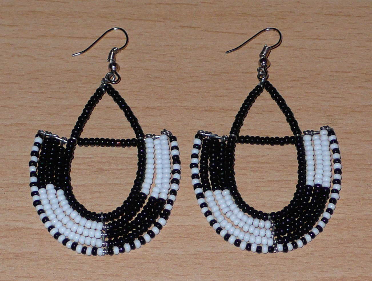 Boucles d'oreilles ethniques Massai chic noires et blanches en forme d'ancres ; elles mesurent 7 cm de long et 4 cm de large et se portent sur des oreilles percées.