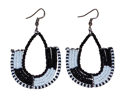 Boucles d'oreilles ethniques bicolores en forme d'ancres composées de perles de rocaille noires et blanches glissées sur des structures géométriques en fils de fer. De taille moyenne, ces boucles d'oreilles aux accents afro chic mesurent 7 cm de long et 4 cm de large ; elles se portent avec des crochets en acier inoxydable sur des oreilles percées.
