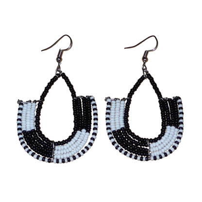 Boucles d'oreilles ethniques bicolores en forme d'ancres composées de perles de rocaille noires et blanches glissées sur des structures géométriques en fils de fer. De taille moyenne, ces boucles d'oreilles aux accents afro chic mesurent 7 cm de long et 4 cm de large ; elles se portent avec des crochets en acier inoxydable sur des oreilles percées.