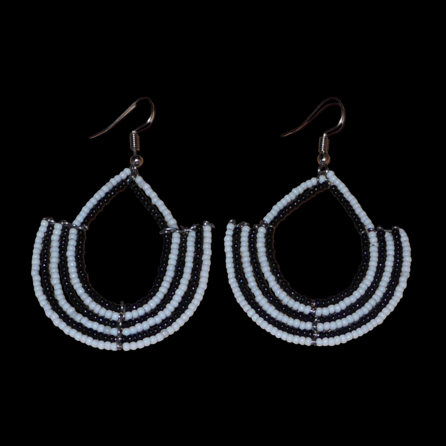 Boucles d'oreilles bicolores afro chic noires et blanches en forme d'ancres composées de perles de rocaille. De taille moyenne, elles mesurent 7 cm de long et 4 cm de large et se portent avec des crochets en acier inoxydable sur des oreilles percées.