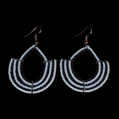 Boucles d'oreilles bicolores afro chic noires et blanches en forme d'ancres composées de perles de rocaille. De taille moyenne, elles mesurent 7 cm de long et 4 cm de large et se portent avec des crochets en acier inoxydable sur des oreilles percées.