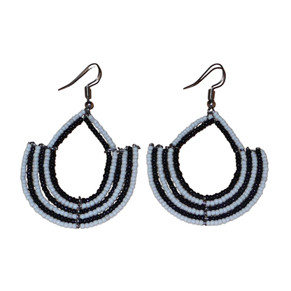 Boucles d'oreilles bicolores afro chic noires et blanches en forme d'ancres composées de perles de rocaille. De taille moyenne, elles mesurent 7 cm de long et 4 cm de large et se portent avec des crochets en acier inoxydable sur des oreilles percées.