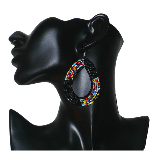 Longues boucles d'oreilles multi-rangs noires et multicolores en forme de gouttes composées de perles de rocaille. Elles mesurent 8 cm de long sur 5 cm de large ; et se portent avec des crochets sur des oreilles percées.