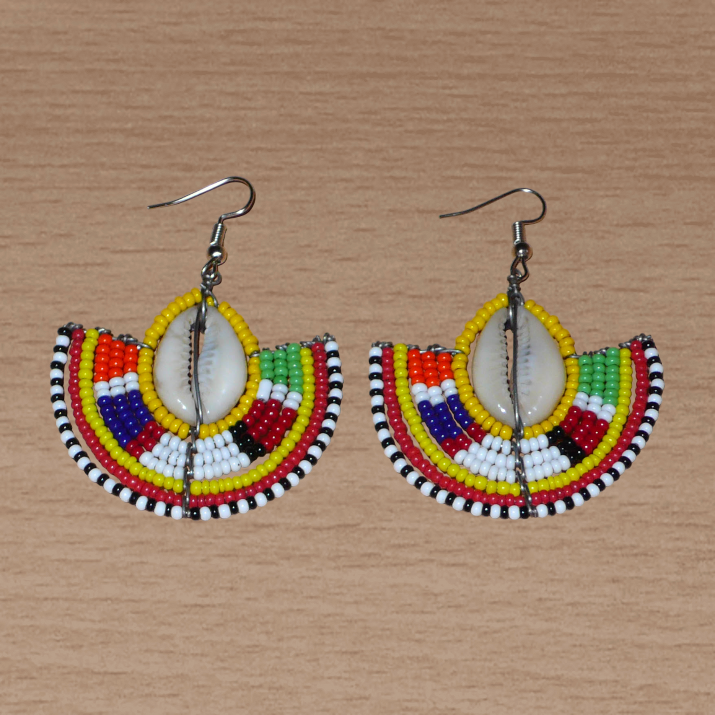 Ces jolies boucles d'oreilles à l'allure ethnique afro chic se composent de perles de rocaille jaunes et multicolores et de coquillages cauris. De taille moyenne, elles mesurent 6 cm de long et 4.5 cm de large, et se portent avec des crochets en acier inoxydable sur des oreilles percées.