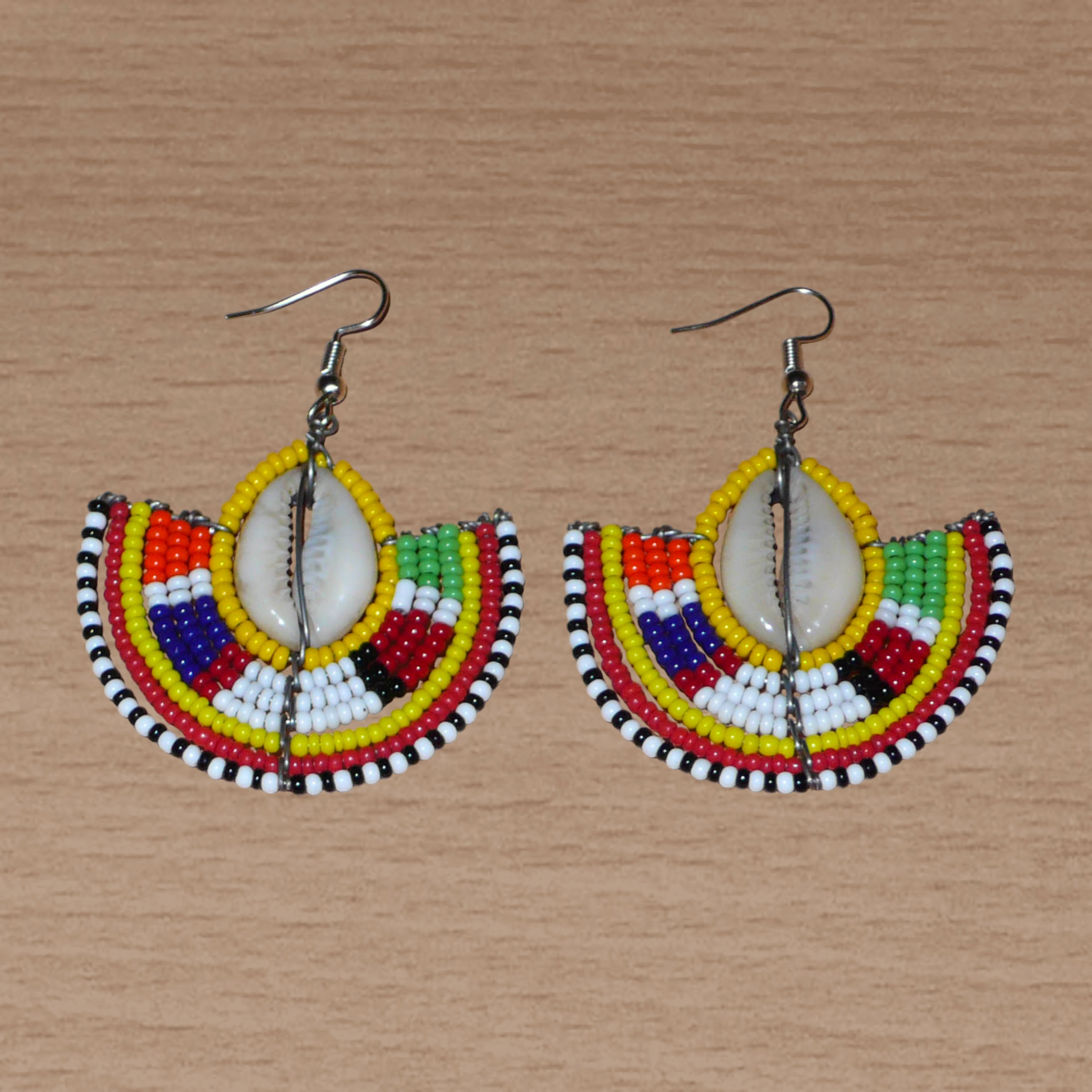 Ces jolies boucles d'oreilles à l'allure ethnique afro chic se composent de perles de rocaille jaunes et multicolores et de coquillages cauris. De taille moyenne, elles mesurent 6 cm de long et 4.5 cm de large, et se portent avec des crochets en acier inoxydable sur des oreilles percées.