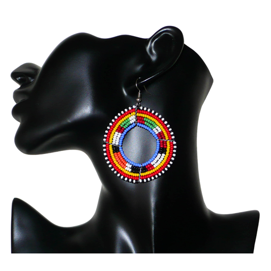 Boucles d'oreilles africaines rondes traditionnelles à motifs ethniques Massai composées de perles de rocaille bleues et multicolores glissées sur des structures circulaires en fils de fer. Ces créoles perlées aux accents afro chic des années 70 mesurent 7 cm de long et 5 cm de large ; elles se portent avec des crochets en acier inoxydable sur des oreilles percées.