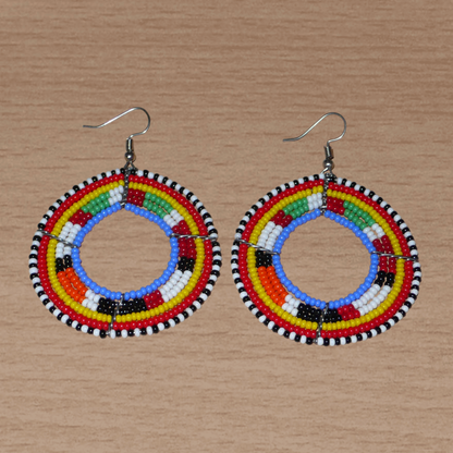 Boucles d'oreilles africaines rondes traditionnelles à motifs ethniques Massai composées de perles de rocaille bleues et multicolores. Ces créoles perlées mesurent 7 cm de long et 5 cm de large ; elles se portent avec des crochets en acier inoxydable sur des oreilles percées.